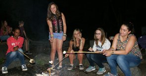 Jugendliche sitzen am Lagerfeuer und grillen Marshmallows