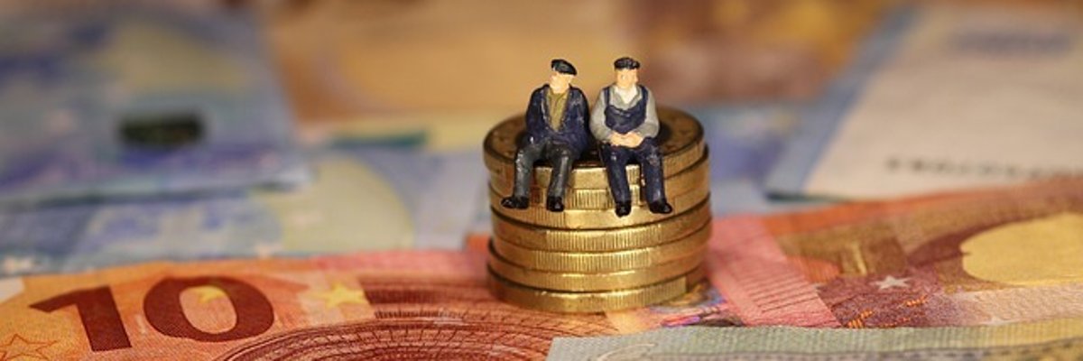 Foto: Auf verstreuten Geldscheinen steht ein Münzstapel. Darauf sitzen zwei ältere Personen in Form von kleinen Plastikfiguren.