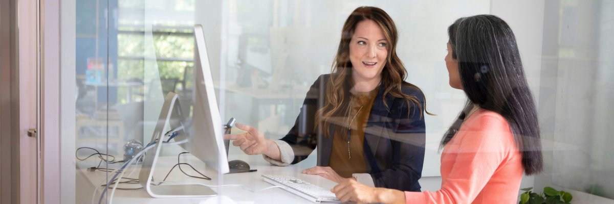 Beratungsgespräch Zwei Frauen stehen am Stehtisch vor dem Bildschirm und reden miteinander über fachliche Themen