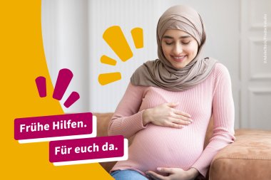 Zwei Frauen sitzen auf einer Couch. Eine füttert das Baby mit der Flasche.