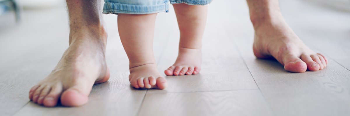 Papafüße und Kleinkindfüße die gemeinsam laufen