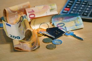 Foto Wohngeld Foto: Auf einer Tischplatte liegen ein Wohnungsschlüssel, Geld und ein Taschenrechner.