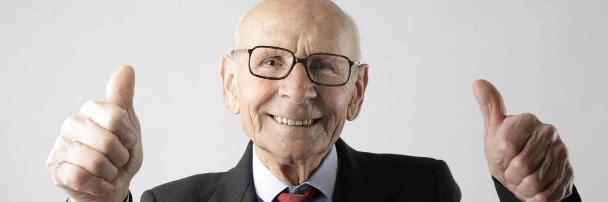 Senior Foto: Ein älterer, lachender Mann reckt beide Daumen nach oben.