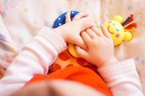 Foto: Hände eines Babys, die ein Spielzeug halten.