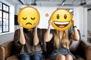 Foto: Zwei Jugendliche sitzen auf einem Sofa. Vor ihren Gesichtern ist ein lachender bzw. ein trauriger Smiley.