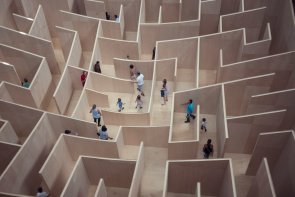 Foto: Sicht von oben auf ein Labyrinth, durch das verschiedene Menschen laufen.