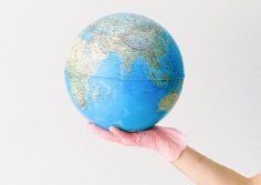 Foto: Weltkugel auf einer Hand mit Latexhandschuh