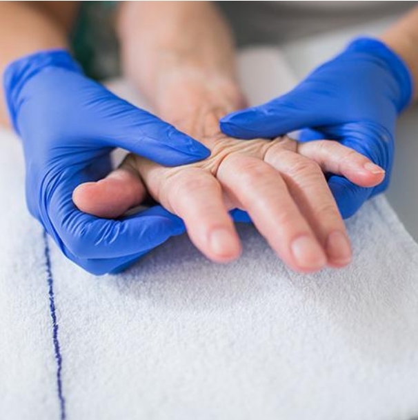 Hände einer Pflegekraft, die Hände eines Patienten halten.
